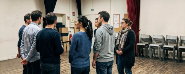 Groupe d'adultes sur une scène de théâtre parisien lors d'une répétition bienveillante